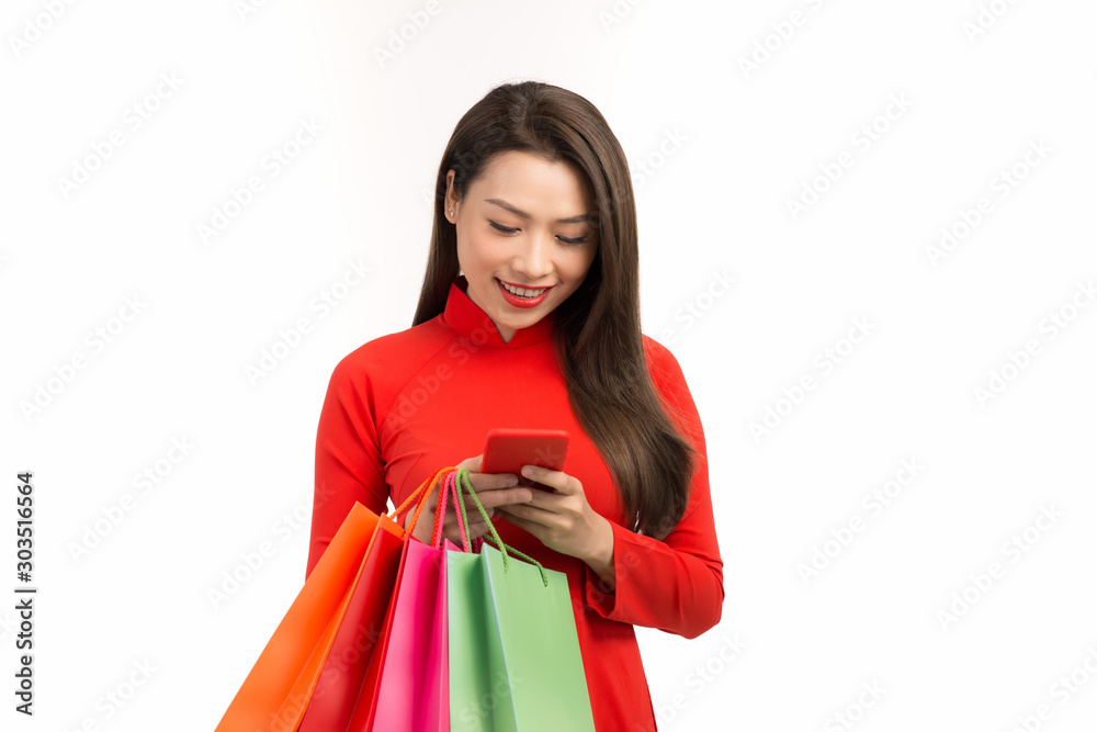Beauty asian woman with Vietnamese dress, chinese new year using smartphone technology shopping online and hold bag Beauty asian woman with Vietnamese dress, chinese new year using smartphone technology shopping online and hold bag
