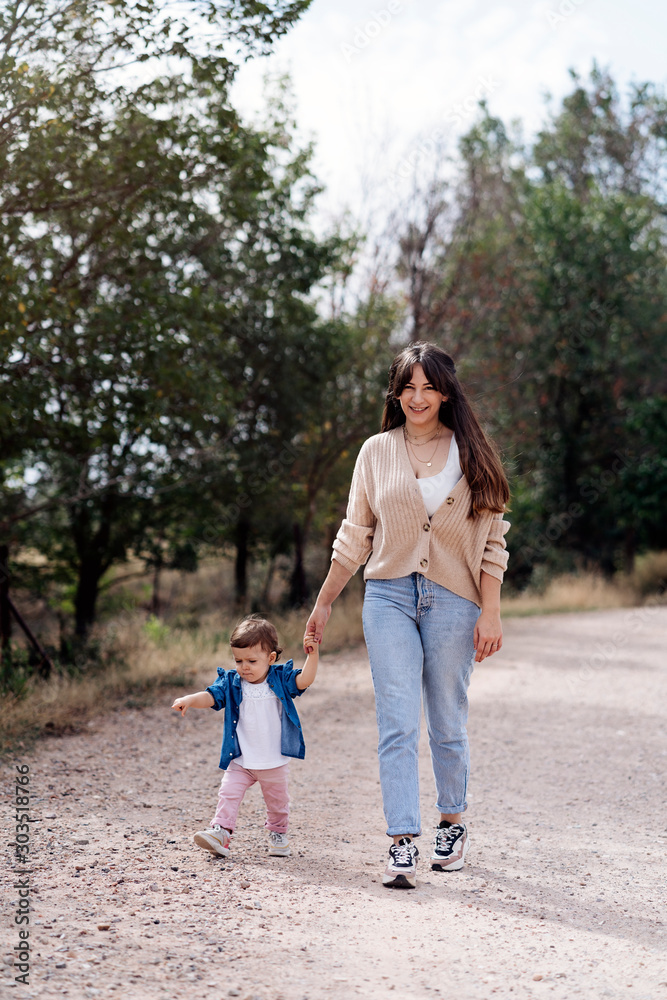Happy mother looking at camera with her daughter walking together in the nature Happy mother looking at camera with her daughter walking together in the nature