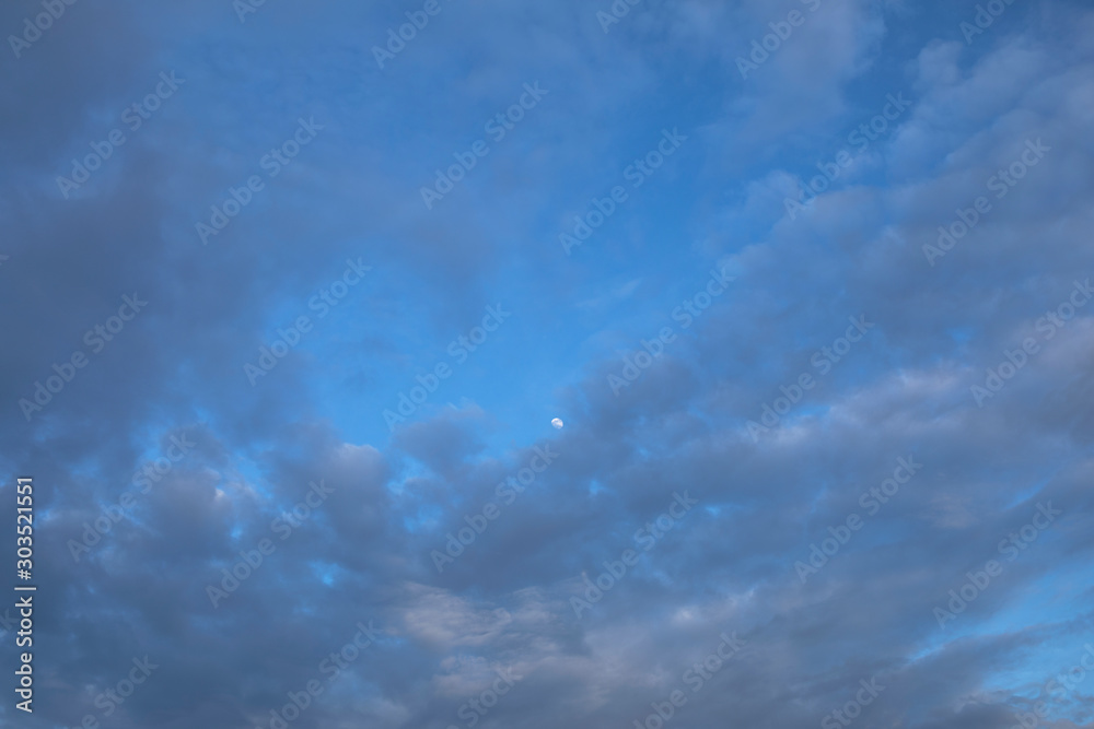 Obraz premium Mystical moon far away on blue evening sky with whirlwind purple clouds