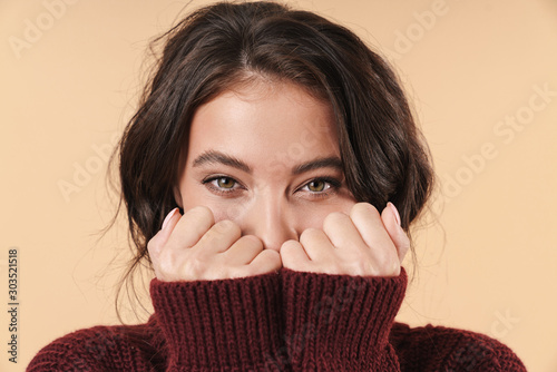 Happy young brunette woman covering face with hands.