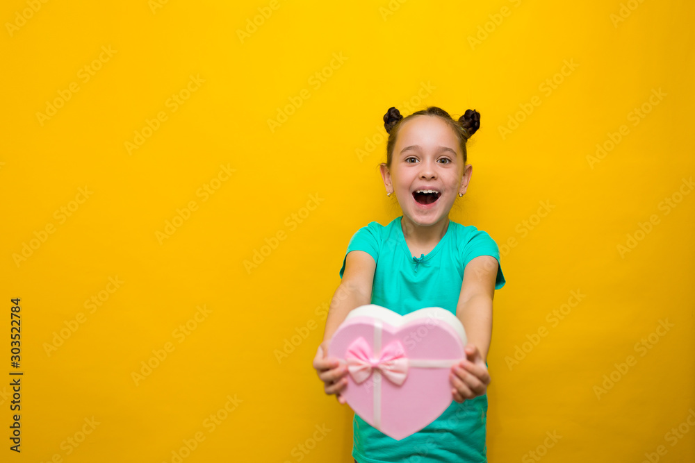 happy little girl with tails standing isolated over yellow background holding shopping pink bag. smiles thoughtfully happy little girl with tails standing isolated over yellow background holding shopping pink bag. smiles thoughtfully