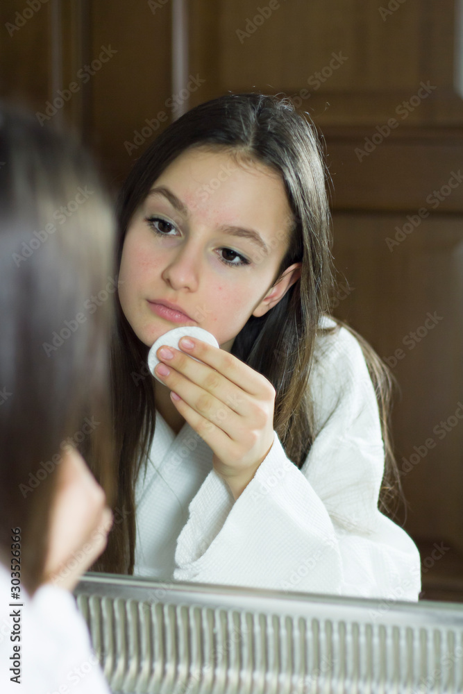 Teenage girl cleaning her face with cotton pads. Skin care and beauty concept Teenage girl cleaning her face with cotton pads. Skin care and beauty concept