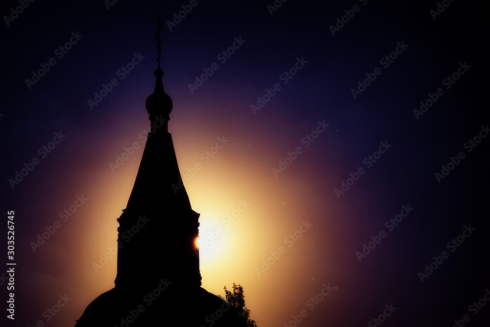 The dome of the Orthodox Church in the evening sun. Dark cloudy sky in anticipation of the night. The ball of the sun against the background of the temple.