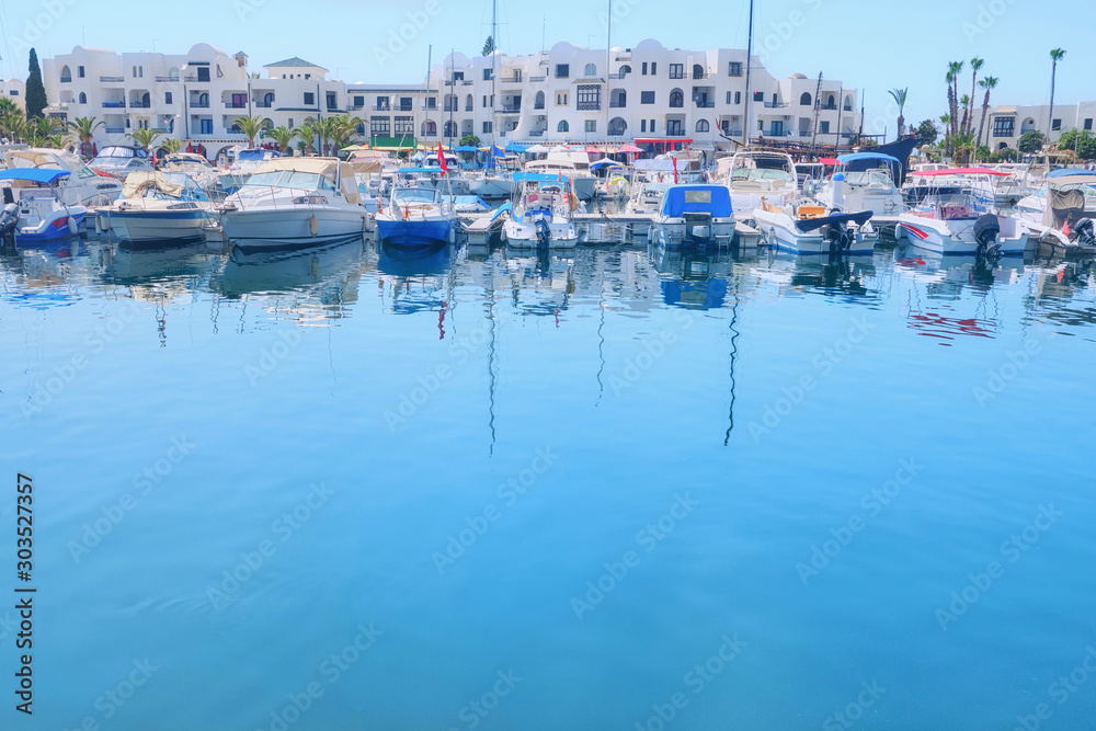 Yachts and boats at the pier on the background of white arabic house at the blue water, copy space