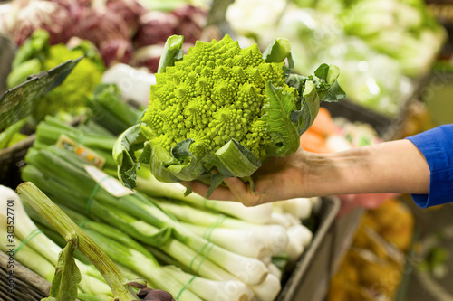 Woman's hand choosing roman cauliflower in the market. Concept of healthy food, bio, vegetarian, diet.