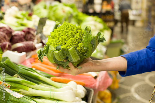 Woman s hand choosing roman cauliflower in the market. Concept of healthy food  bio  vegetarian  diet.