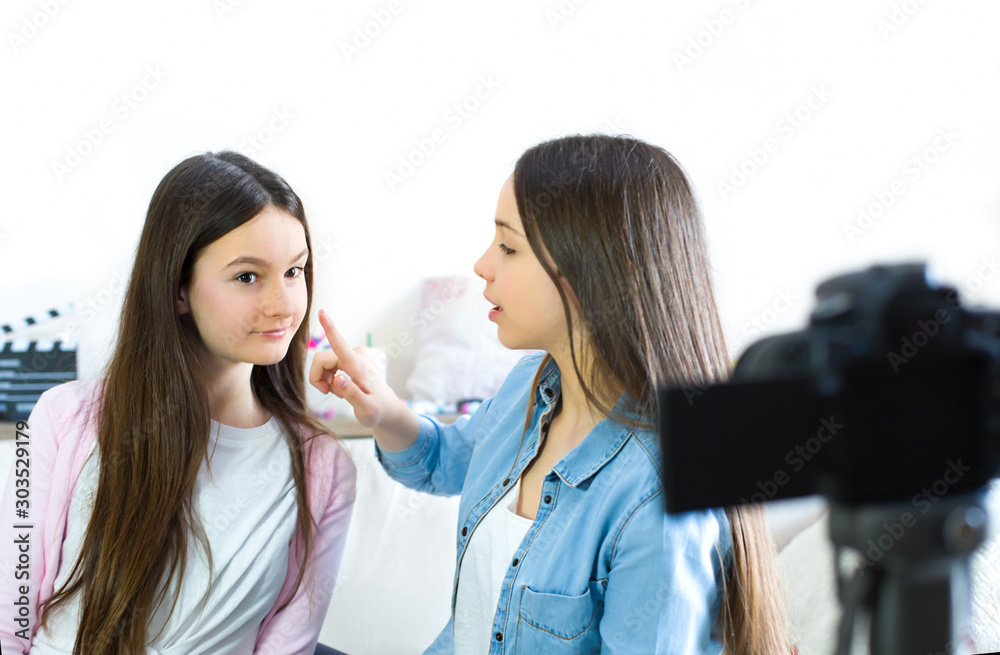 Two beauty blogger cute girls presenting beauty cosmetic products and broadcasting live video to social network. Focus on the blogger teen girls influencer. Beauty blogger and vlog concept. Two beauty blogger cute girls presenting beauty cosmetic products and broadcasting live video to social network. Focus on the blogger teen girls influencer. Beauty blogger and vlog concept.