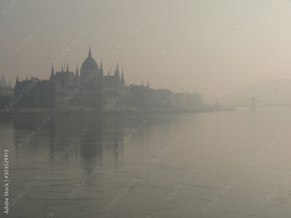 Silhouette of the neo-Gothic palace in the parliament of budapest on the danube river shrouded in fog.