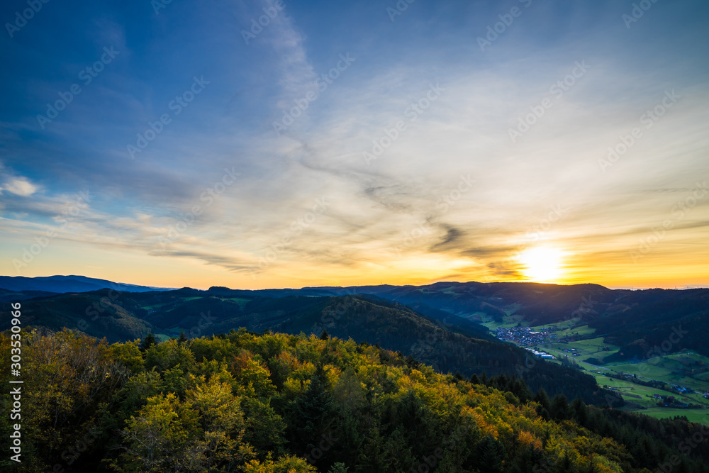 Germany, Endless view over beautiful untouched natural black forest nature landscape above tree tops in warm orange sunset light in autumn season