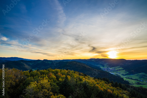 Germany, Endless view over beautiful untouched natural black forest nature landscape above tree tops in warm orange sunset light in autumn season