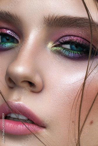 Photo A very close up photo of young model with blue eyes, rainbow eyeshadows and perfect skin