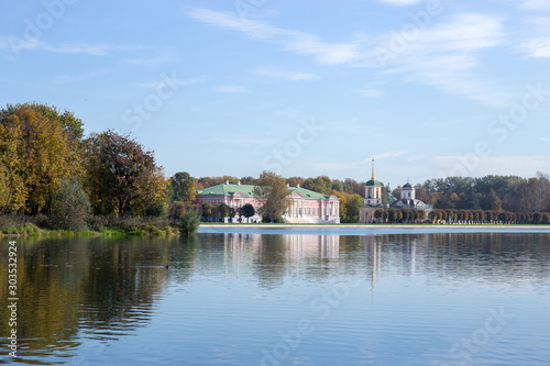 The old beautiful house stands on the shore of a pond surrounded by autumn trees. Kuskovo, Moscow, Russia.