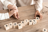 cropped view of retired couple sitting near wooden cubes with alzheimer letters