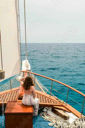 Rear view portrait of woman on a ship looks into the distance at blue ocean © smspsy