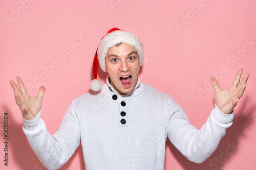 Man in a white sweater and red Santa hat is very excited to celebrate Christmas and New Year.