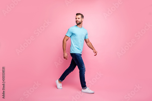 Photo of turned man in jeans denim walking forward looking back in sneakers isolated pastel color background