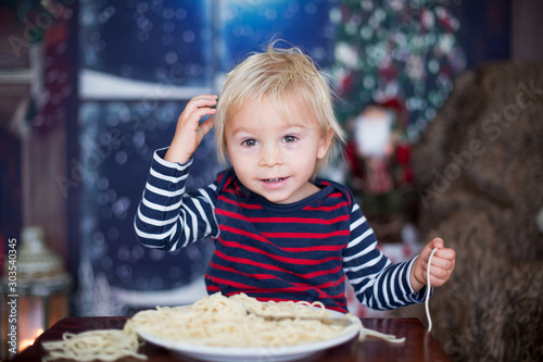 Sweet toddler child  boy  eating spaghetti at home