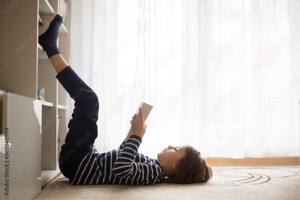 Cute child, boy, reading a book at home - obrazy, fototapety, plakaty 