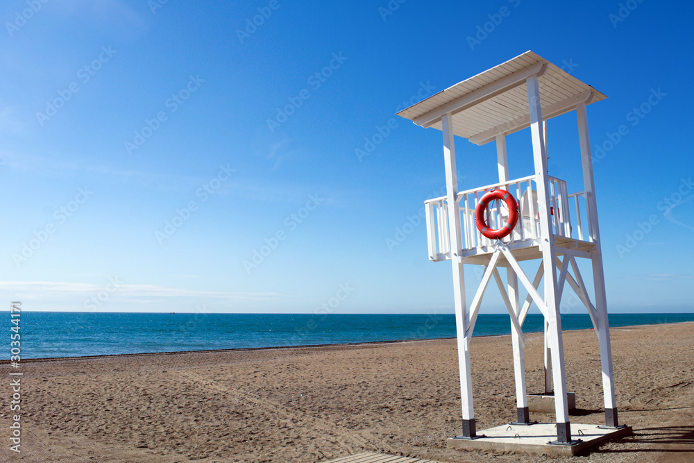 A bright sunny day at Torrox Costa, on the Costa del Sol, Spain. A view of the lifeguards station on the pristine beach. Clear blue sky - copy space. A bright sunny day at Torrox Costa, on the Costa del Sol, Spain. A view of the lifeguards station on the pristine beach. Clear blue sky - copy space.