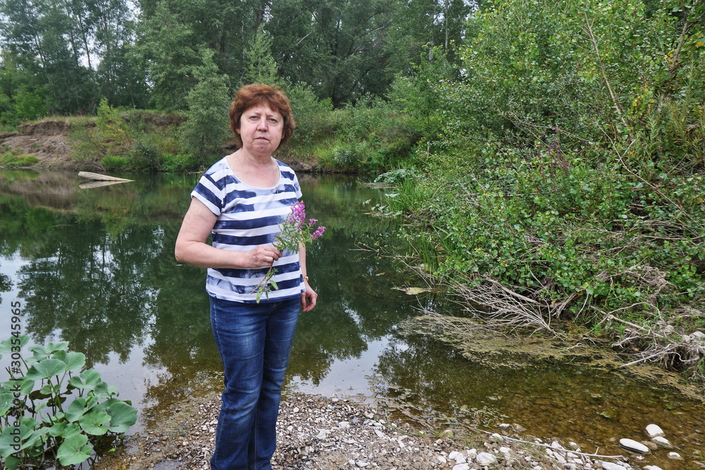 Lady with a flower on the background of the river and the forest Lady with a flower on the background of the river and the forest