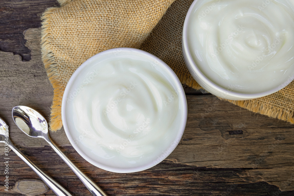 Yogurt greek white clean In bowl with spoon on a wooden background from top view. Yogurt greek white clean In bowl with spoon on a wooden background from top view.