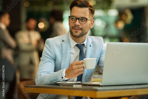 Businessman Using Laptop Whilst Working In Coffee Shop