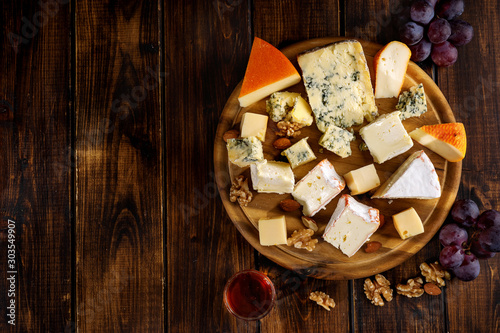 Top view of many cheese sorts served on wooden board