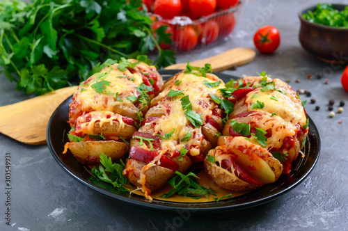 Fototapeta Naklejka Na Ścianę i Meble -  Hasselback potato stuffed with salami, cheese, ketchup, garlic and herbs. Baked whole potatoes is sliced and stuffed. Traditional swedish recipe.
