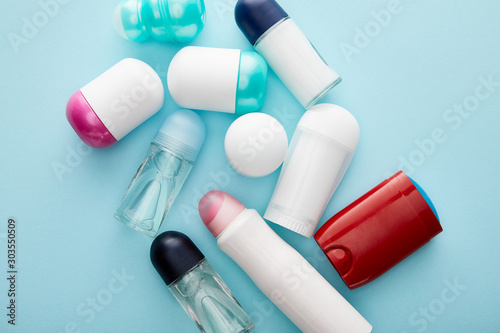 top view of roll on and spray bottles of deodorant on blue background photo