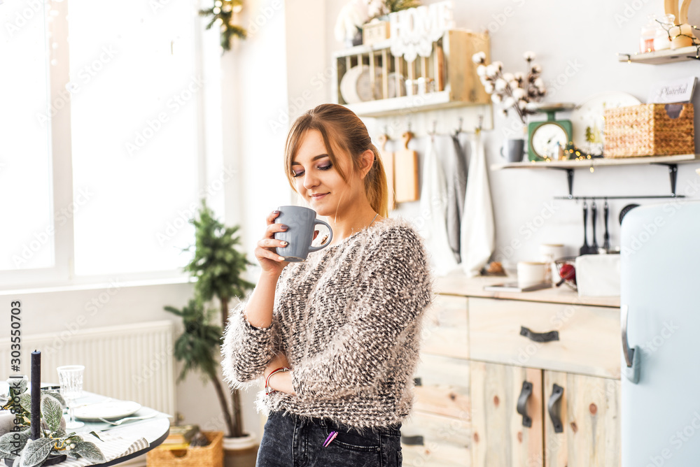 beautiful blonde with a cup of cocoa in the kitchen with Christmas decor beautiful blonde with a cup of cocoa in the kitchen with Christmas decor