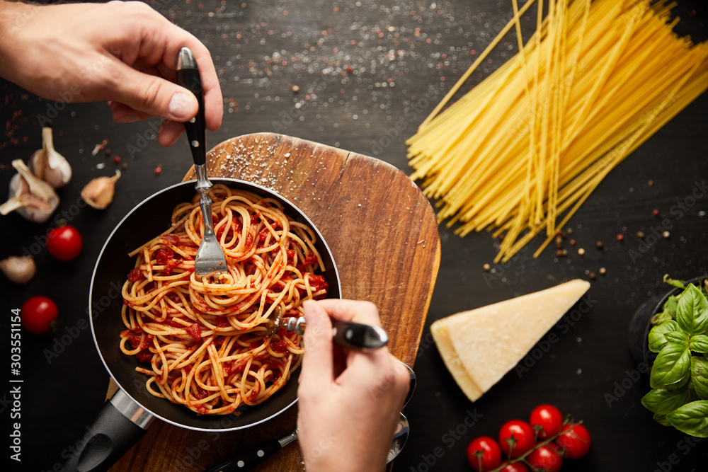 Φωτογραφία cropped view of couple eating tasty bolognese pasta from frying pan near ingredi