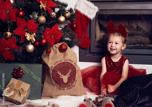 little girl with gift in front of christmas tree