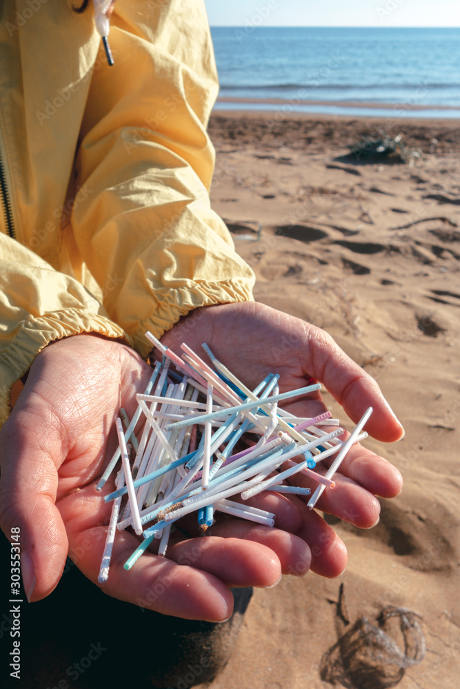 Hands full of plastic ear sticks collected on the beach. Ocean plastic