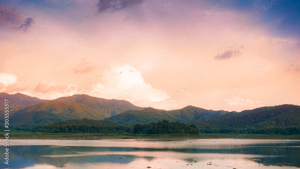 Picture of a lake surrounded by mountains With a backdrop of orange-pink skies.