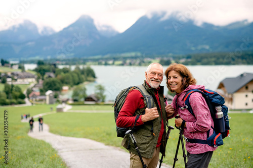 Senior pensioner couple with nordic walking poles hiking in nature.