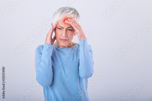 Mature woman holding her head with her hands while having a headache and feeling unwell. Senior woman with headache, pain face expression. Elderly woman having head pain migraine photo