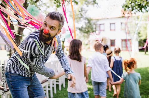 Man with kids on birthday party playing outdoors in garden in summer.