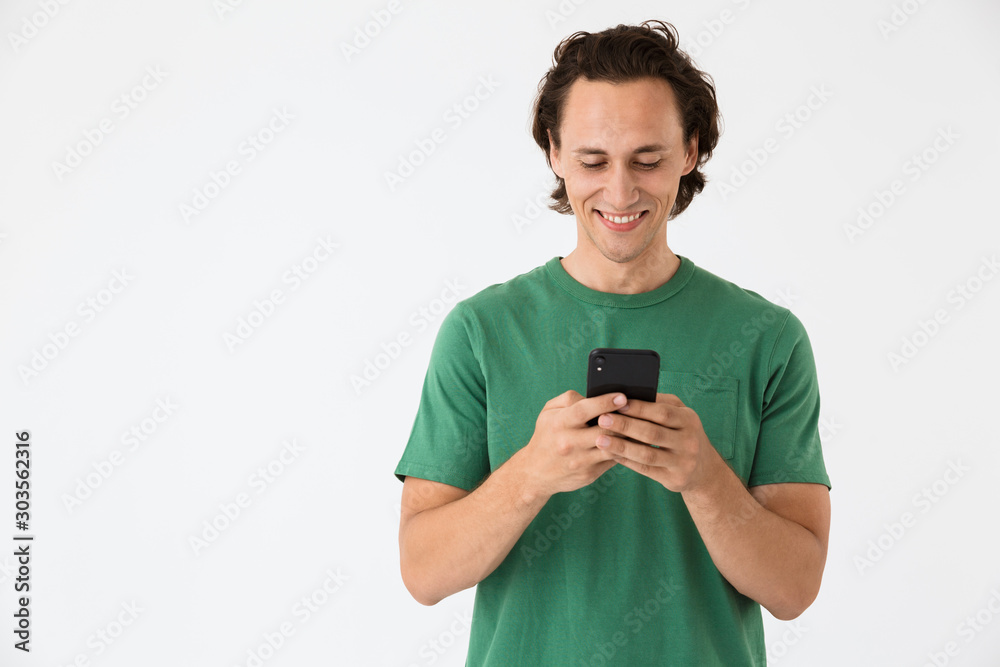 Image of attractive brunette man smiling and holding smartphone Image of attractive brunette man smiling and holding smartphone