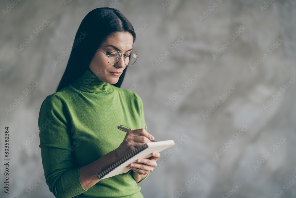 Photo of serious confident woman noting down information heard from employee holding copybook writing with pen isolated concrete grey color background Photo of serious confident woman noting down information heard from employee holding copybook writing with pen isolated concrete grey color background