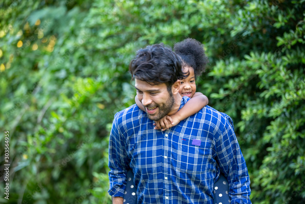 Young mixed race family playing in garden, father and daughter play game on holiday