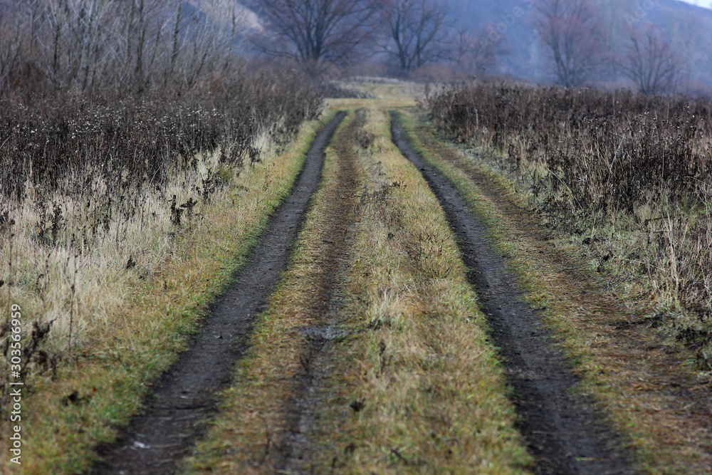 a dirt road stretching into the distance along the river Bank surrounded by hills