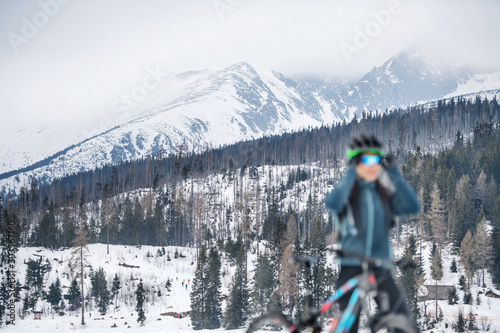 Female mountain biker standing outdoors in winter nature, focus on background.