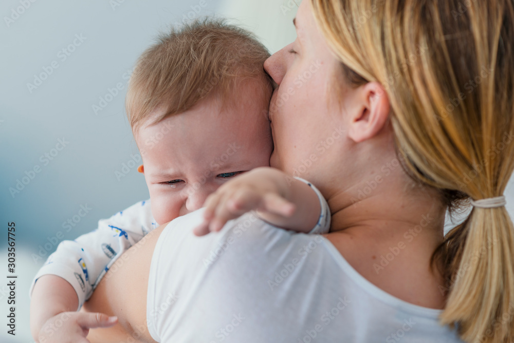 Mother holding crying baby. Young woman with her little son. Mother holding crying baby. Young woman with her little son.