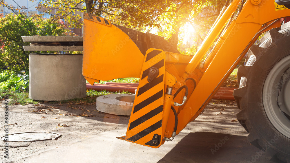 Φωτογραφία Construction machinery tractor loader with hydraulic bucket jaw on the background of well rings