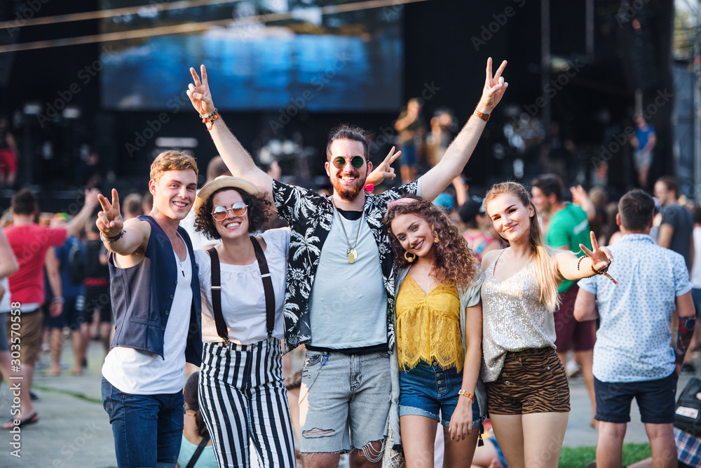 Group of young friends at summer festival. - obrazy, fototapety, plakaty 