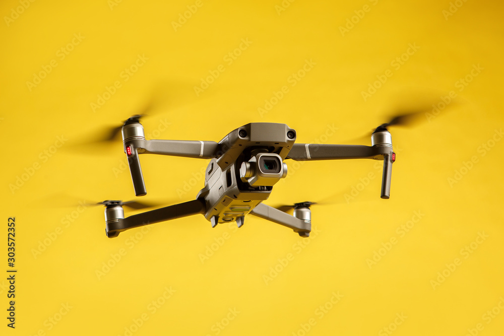 Air drone quadcopter isolated on yellow background in the air launched. Video and aerial photography from height. Air drone quadcopter isolated on yellow background in the air launched. Video and aerial photography from height.