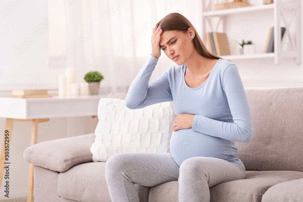 Expectant Woman Touching Head Having Headache Sitting On Couch Indoor Expectant Woman Touching Head Having Headache Sitting On Couch Indoor