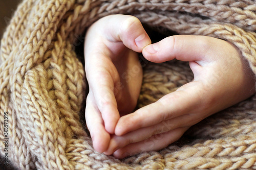 Children's hands in the shape of heart on a knitted scarf