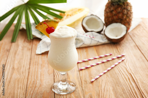 Glass of tasty Pina Colada cocktail and fruits on table