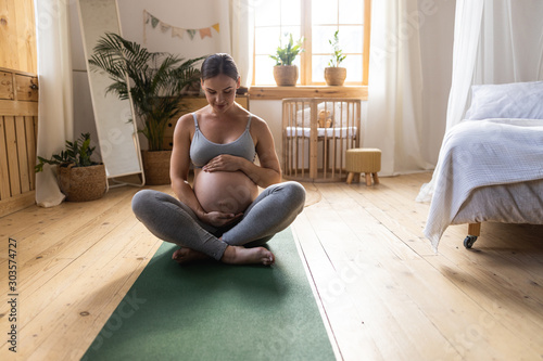 Pretty expectant mother looking at her belly photo